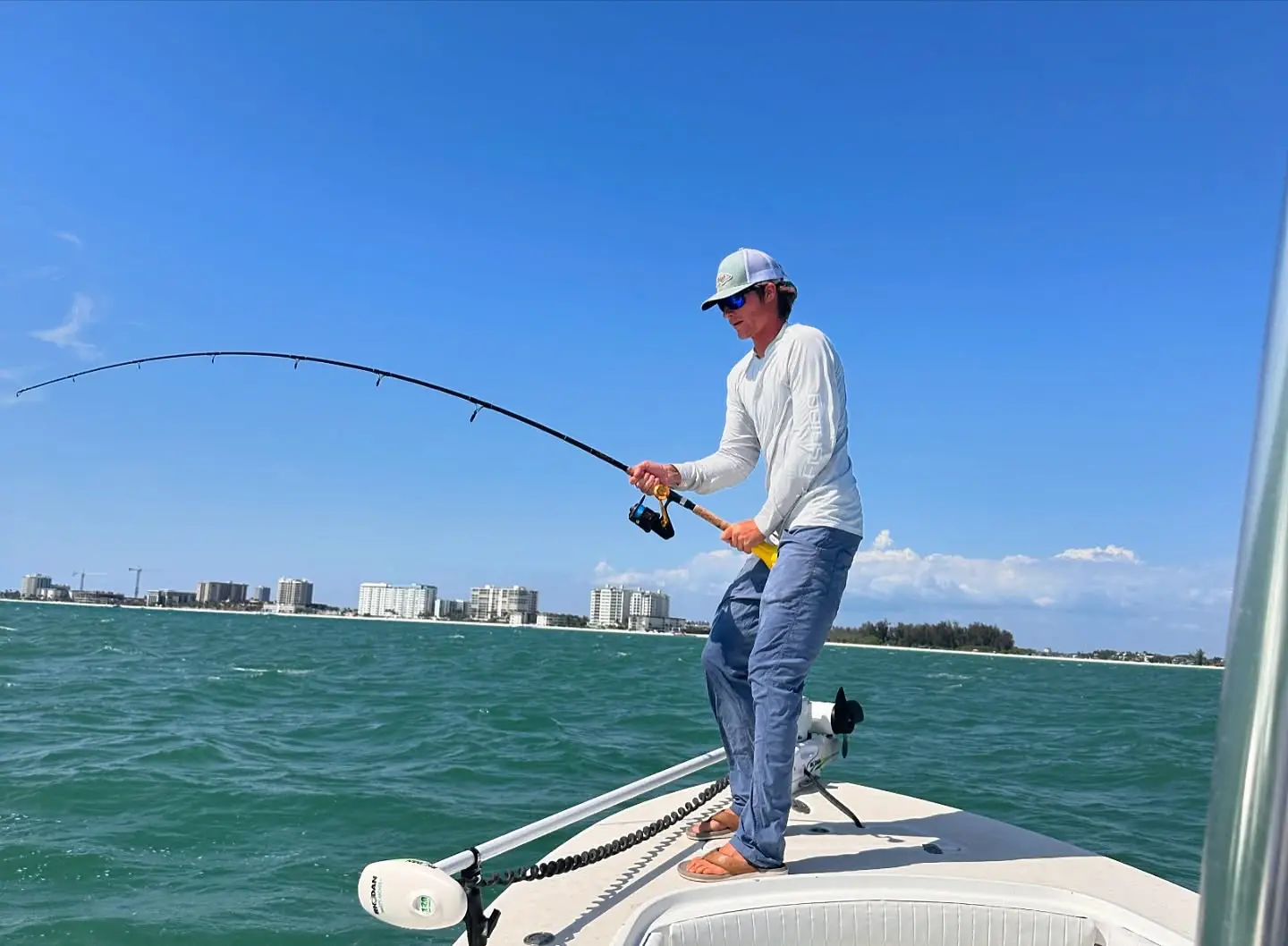 Angler fighting a fish from the bow of a Sarasota fishing charter boat.