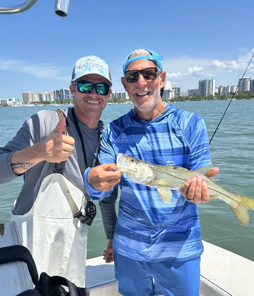 Two anglers holding a snook during a Sarasota fishing charter.