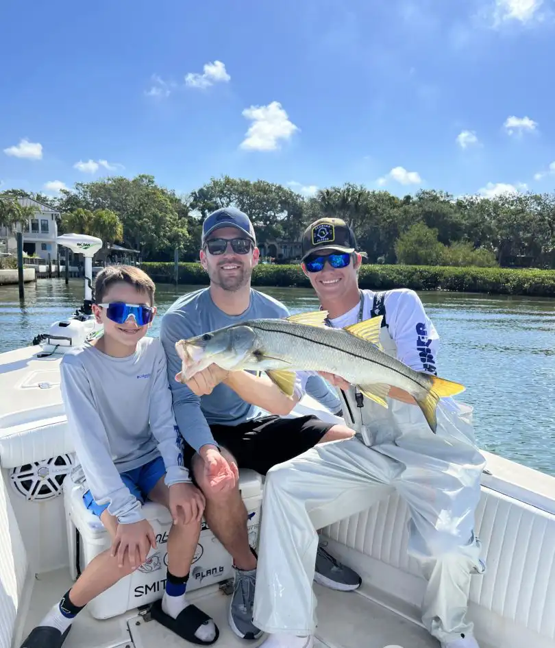 Family posing with a snook during a Sarasota fishing charter.