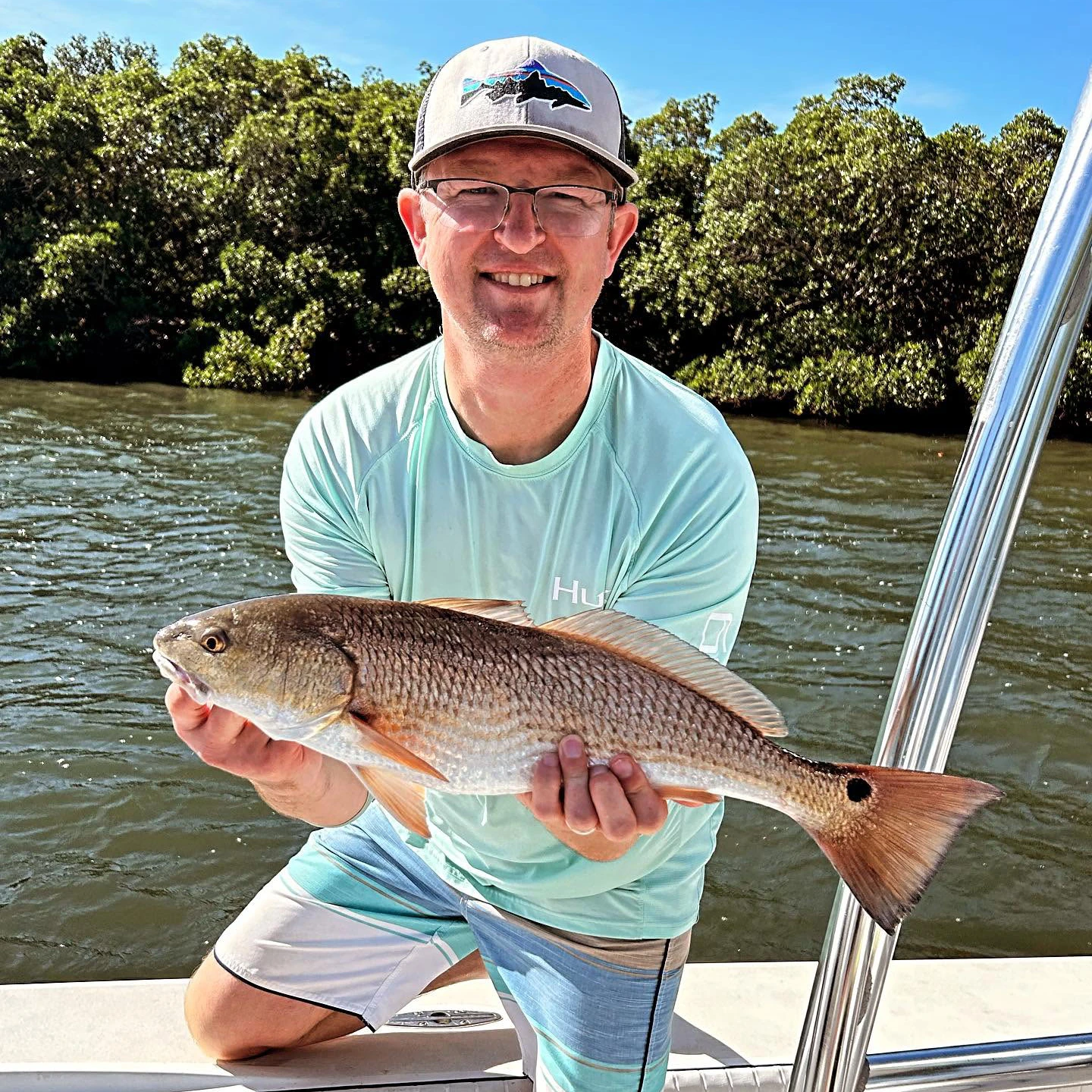 Angler holding a healthy redfish caught during a Sarasota fly fishing charter along the mangrove shoreline.