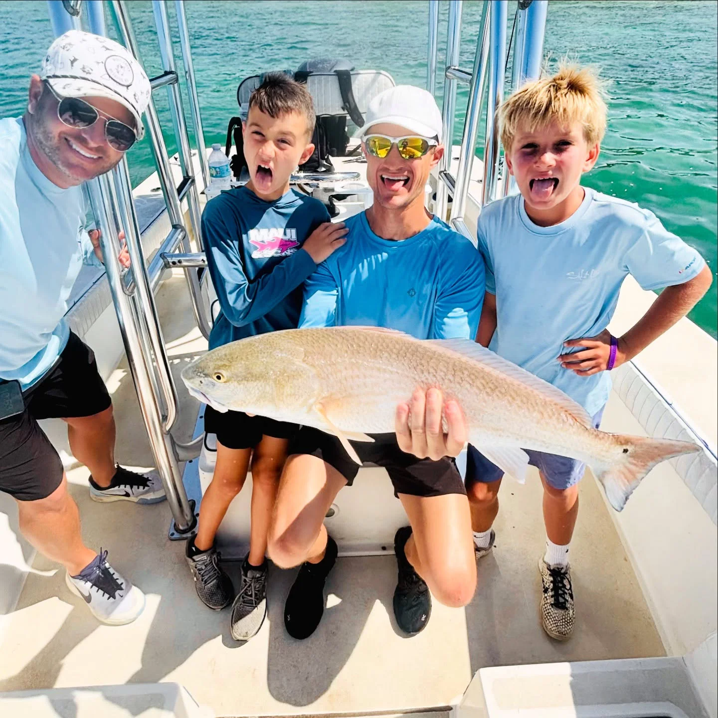 Family with kids holding a redfish during a Sarasota spring break fishing charter.