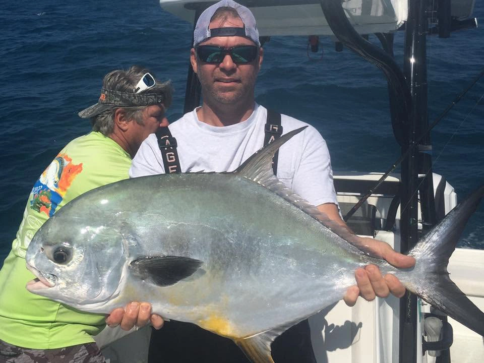 Angler holding a large African pompano aboard a Sarasota fishing charter boat in the Gulf of Mexico.