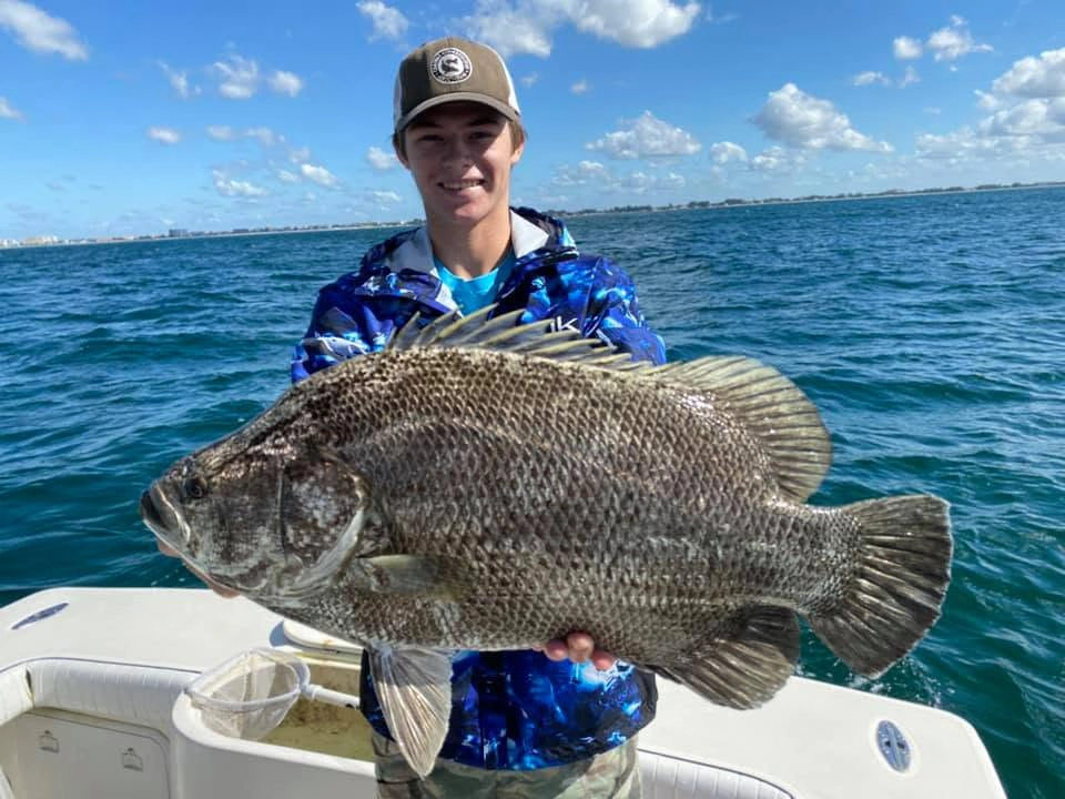 Young angler holding a trophy black drum during a nearshore fishing charter off the coast of Sarasota, Florida.