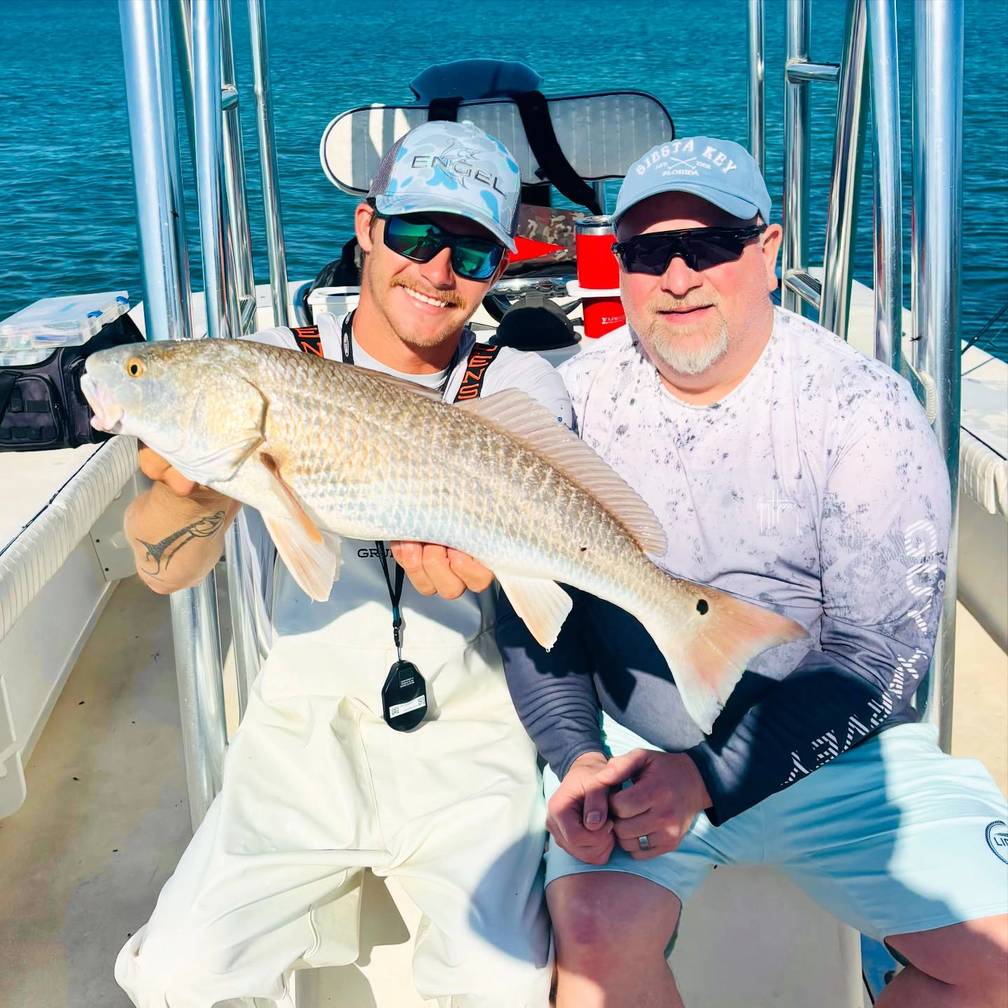 Captain and angler holding a large redfish aboard a Sarasota fishing charter boat on a sunny day.