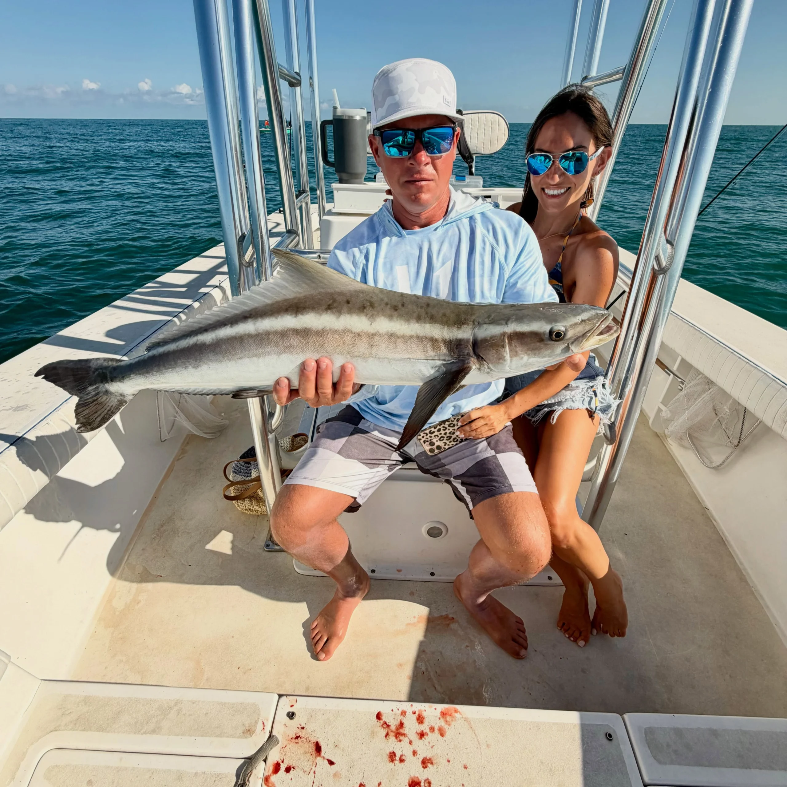 Couple holding a large cobia aboard a Sarasota fishing charter boat on calm Gulf waters.