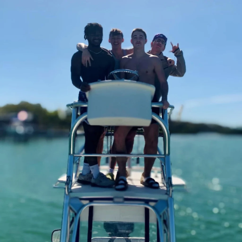 Group of friends enjoying a Sarasota custom charter while standing on the tower of an offshore fishing boat on a sunny day.