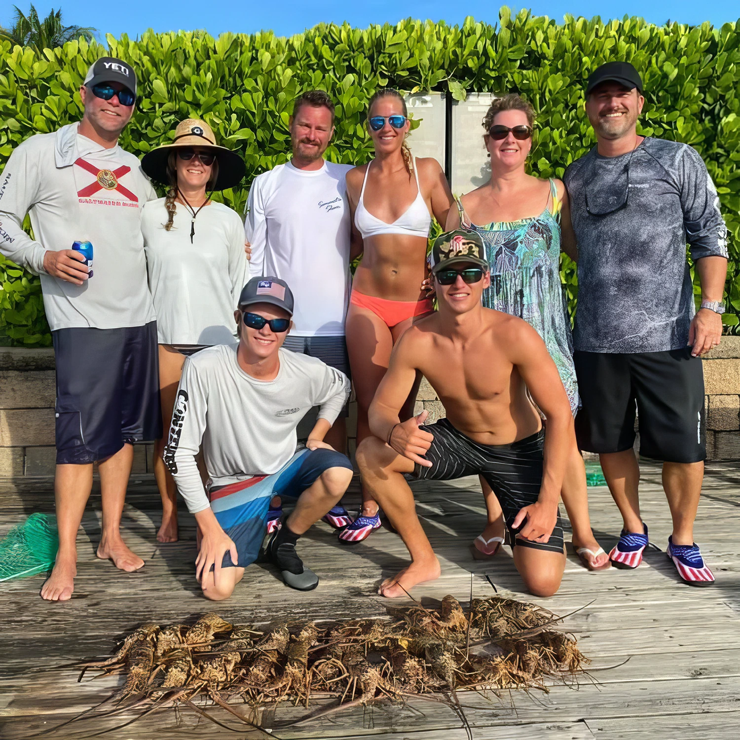 Group of friends posing together after a successful Sarasota custom charter with a large catch of Florida spiny lobsters.