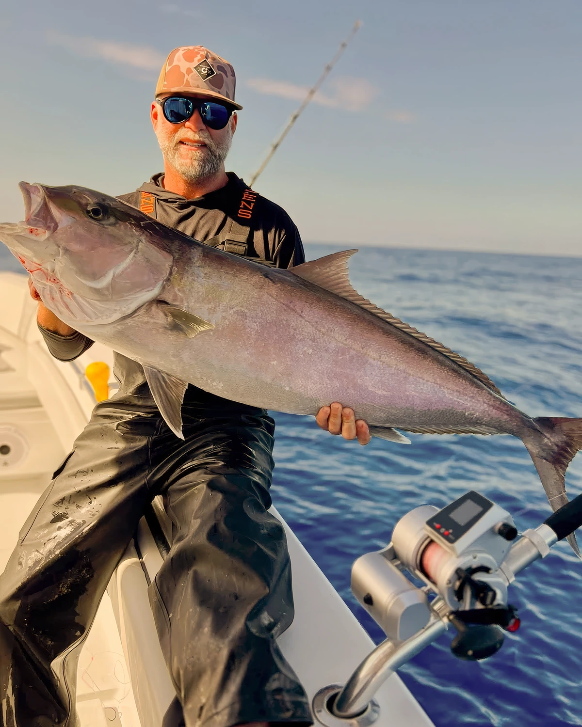 Angler holding a large king mackerel aboard a Sarasota offshore fishing charter boat during calm morning conditions in the Gulf of Mexico.