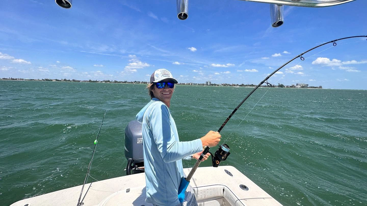 Young angler smiling while fighting a powerful tarpon aboard a Sarasota fishing charter boat on Sarasota Bay.