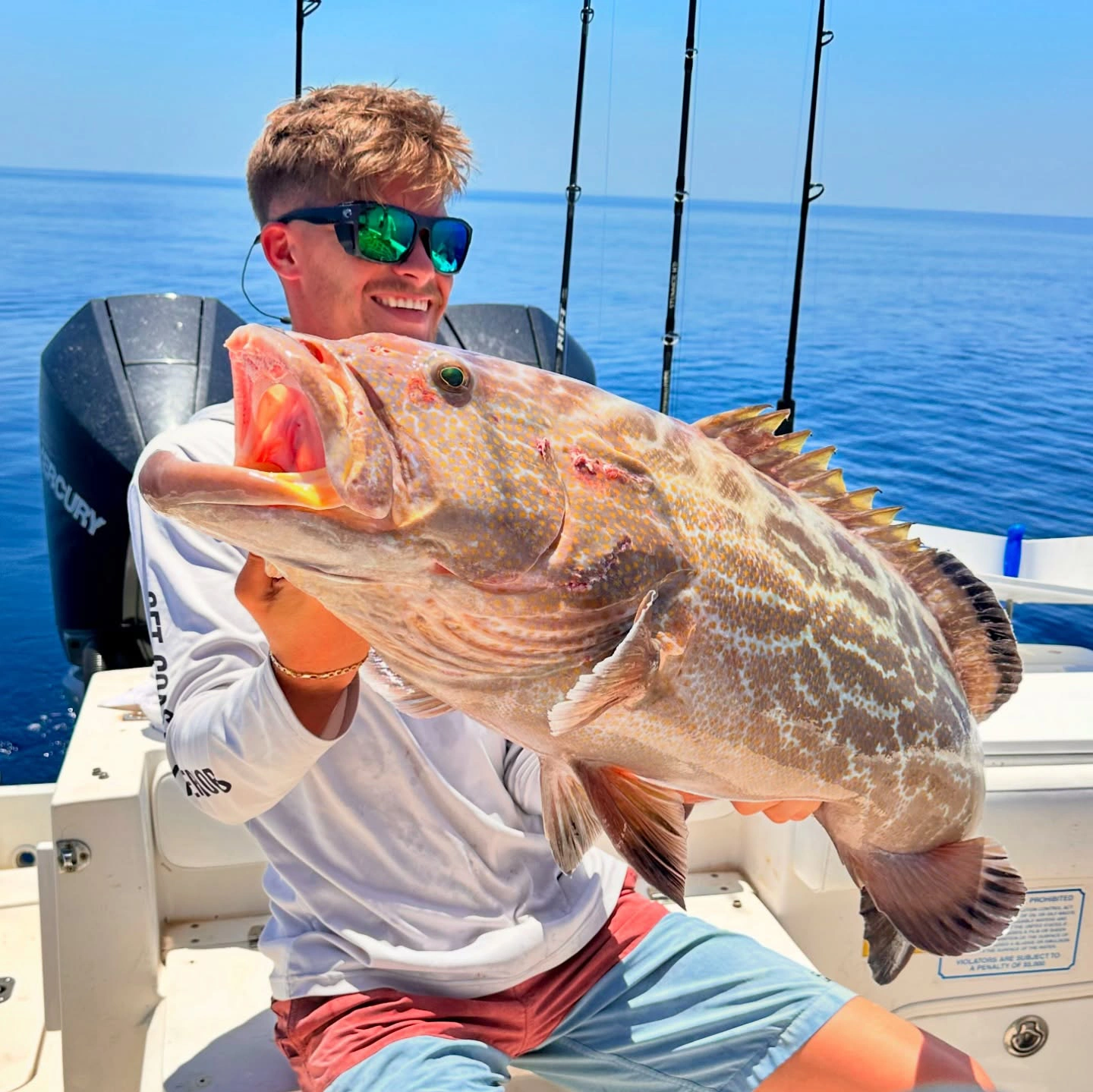 Young angler holding a large gag grouper aboard a Sarasota fishing charter boat in the Gulf of Mexico.