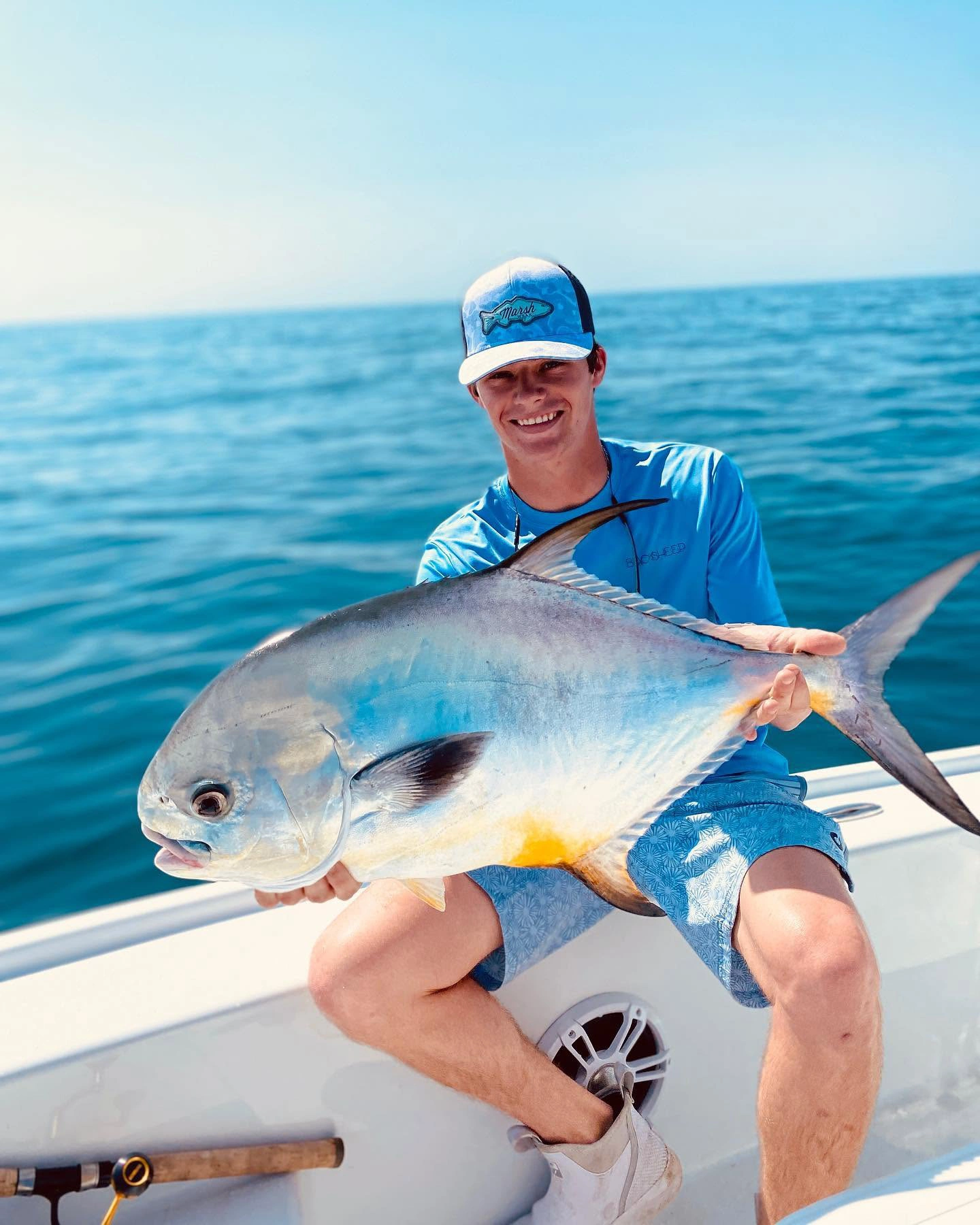 Young angler holding a large African pompano aboard a Sarasota fishing charter boat in the Gulf of Mexico.