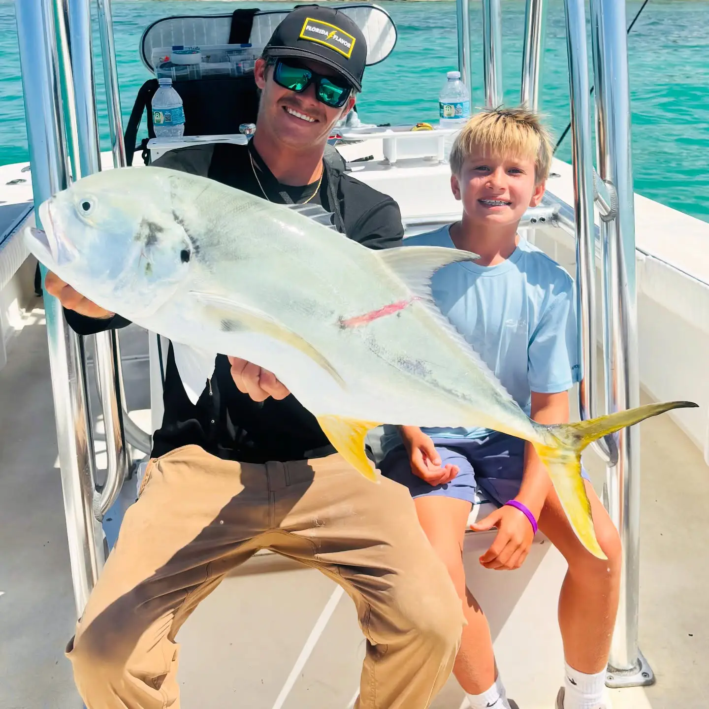 Family fishing trip with father and son holding a trophy African pompano in Sarasota, Florida.