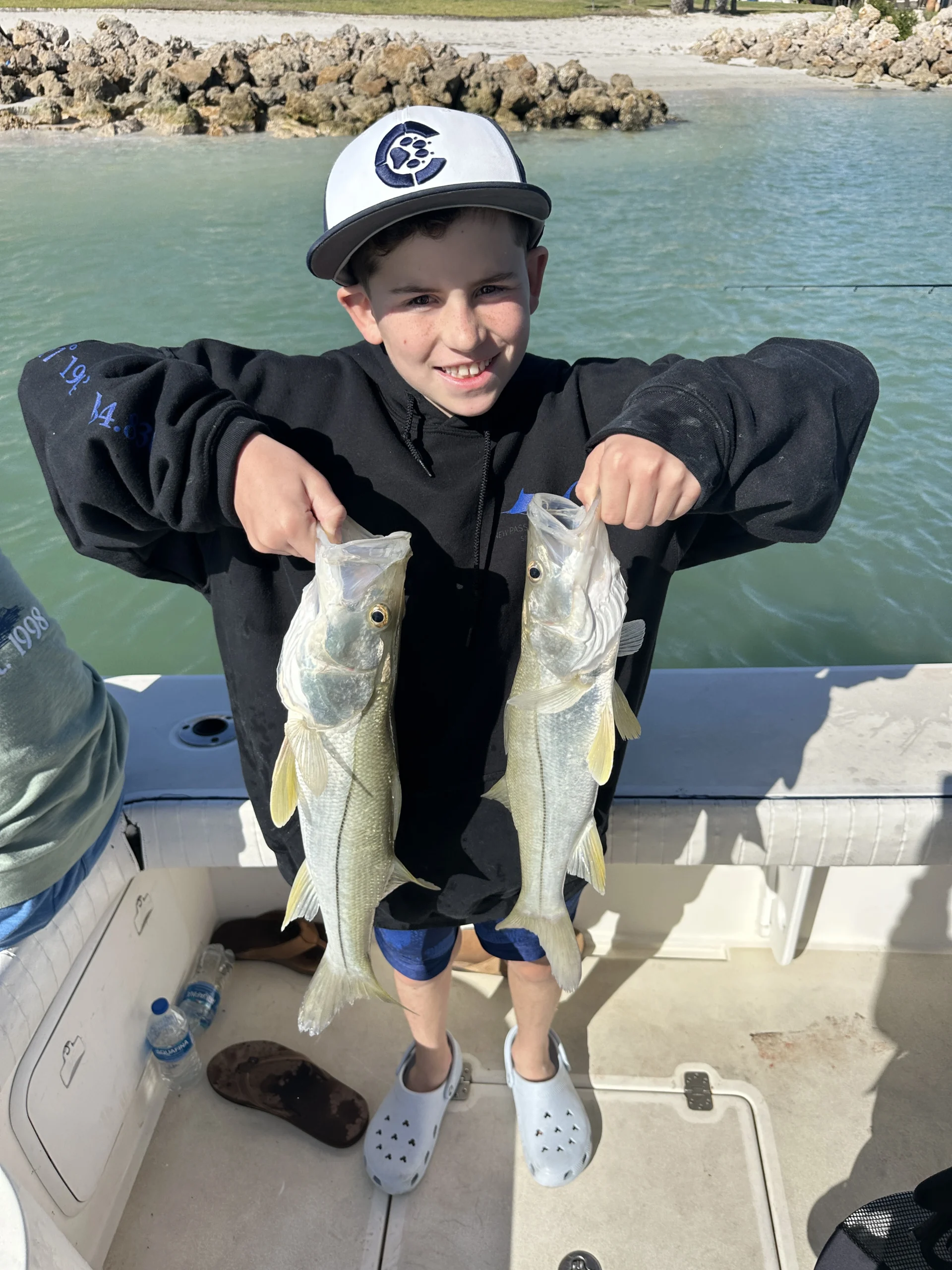 Young angler holding two snook during a successful inshore fishing trip in Sarasota, Florida.