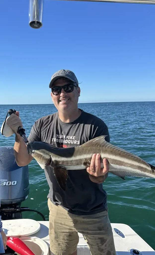 Happy customer holding a cobia caught during a Sarasota fishing charter in Sarasota Bay.
